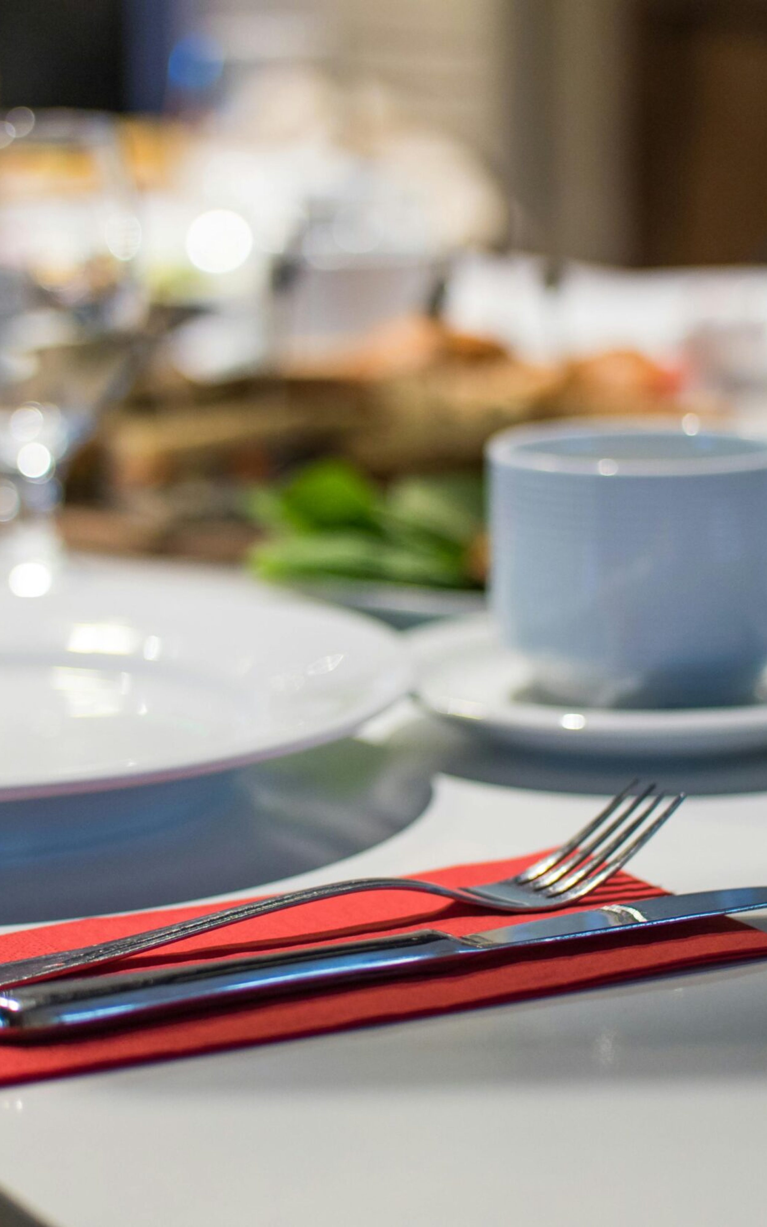 pexels-photo-735869-735869 Close-up of an elegant dining table set with glassware, silverware, and red napkins in a restaurant setting.